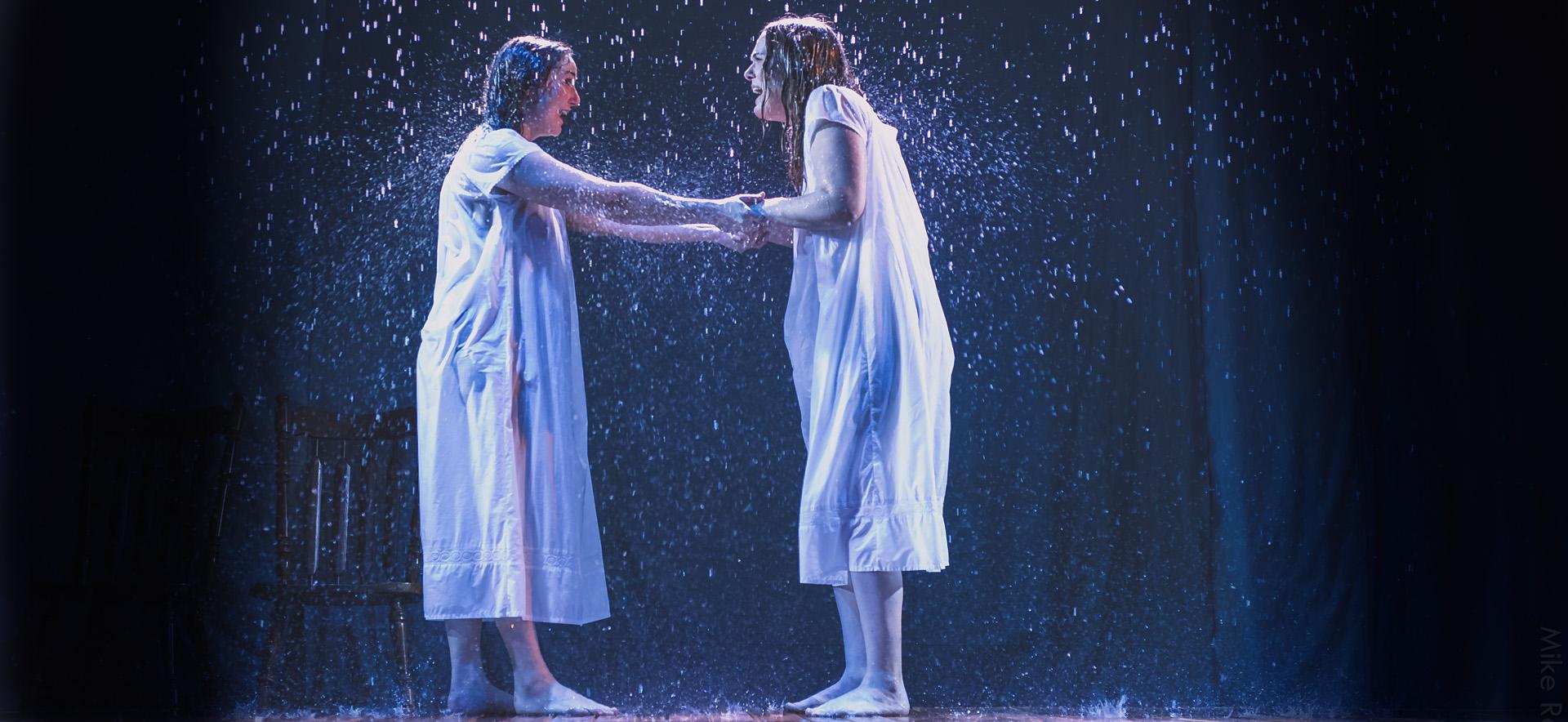 Two women standing under the rain on stage in Alley Reps production of Indecent