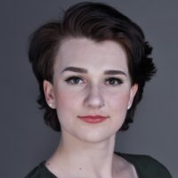 Headshot of an individual, short dark hair, wearing a dark shirt, and a nose piercing